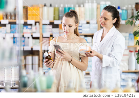 Pregnant woman buyer scans syrup qr code with woman pharmacist 139194212