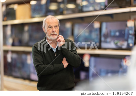 man stands near the TV sets in a store man stands near the TV sets in a store 139194267
