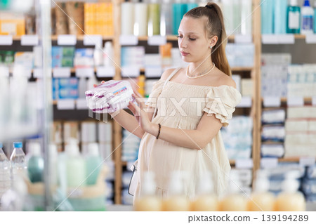 Young pregnant woman are busy choosing feminine pads at pharmacy Young pregnant woman are busy choosing feminine pads at pharmacy 139194289