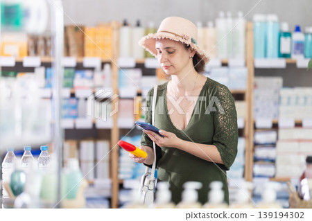 Woman in pharmacy scans QR code on mosquito repellent 139194302