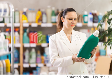 Adult woman buyer chooses detergent in store Adult woman buyer chooses detergent in store 139194305