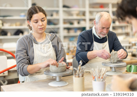 During working day, three pottery workshop workers sculpt from clay, form final product During working day, three pottery workshop workers sculpt from clay, form final product 139194310