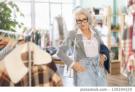 Mature woman standing in store and choosing jeans Mature woman standing in store and choosing jeans 139194329