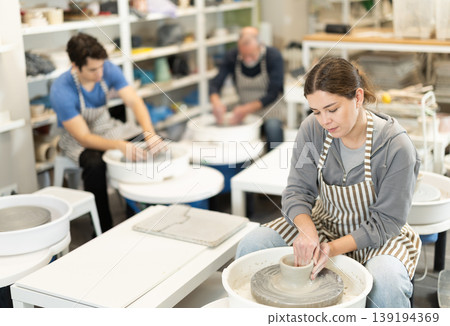Young woman shaping pottery on wheel in ceramics studio 139194369