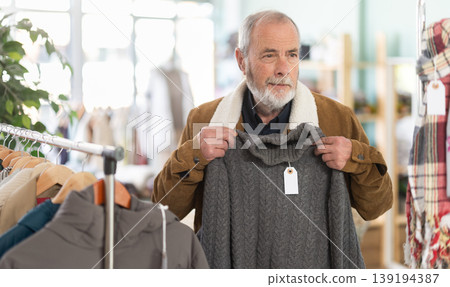Family clothing store, senior man customer choose winter sweater Family clothing store, senior man customer choose winter sweater 139194387