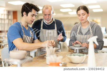 During working day, three pottery workshop workers sculpt from clay, form final product During working day, three pottery workshop workers sculpt from clay, form final product 139194412