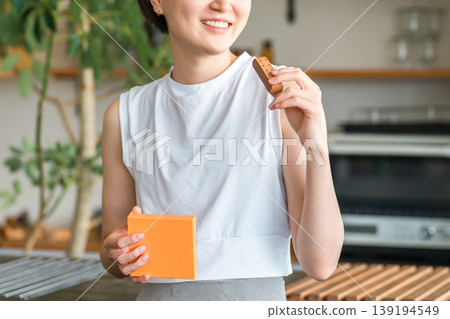 Young Asian woman in yoga wear eating a protein/nutrition bar Young Asian woman in yoga wear eating a protein/nutrition bar 139194549