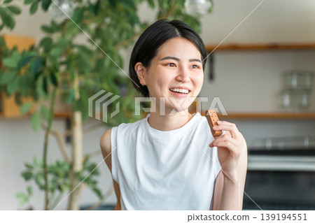 Young Asian woman in yoga wear eating a protein/nutrition bar Young Asian woman in yoga wear eating a protein/nutrition bar 139194551
