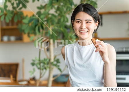 Young Asian woman in yoga wear eating a protein/nutrition bar Young Asian woman in yoga wear eating a protein/nutrition bar 139194552