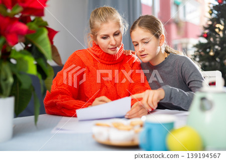 Mom together with daughter write a congratulatory letter during christmas time Mom together with daughter write a congratulatory letter during christmas time 139194567