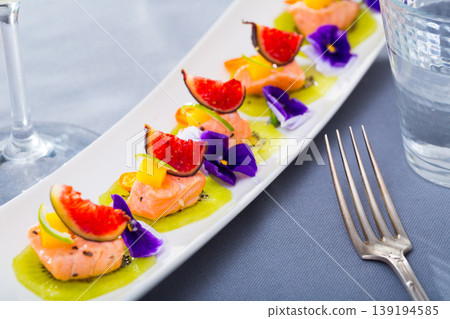 Ceviche from red trout on plate with cumquat, kiwi, figs and flower 139194585
