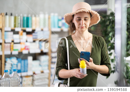 Middle-aged woman scanning barcode on repellent in chemist's shop Middle-aged woman scanning barcode on repellent in chemist's shop 139194588