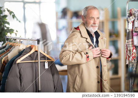 Elderly man trying on brown jacket in store Elderly man trying on brown jacket in store 139194590