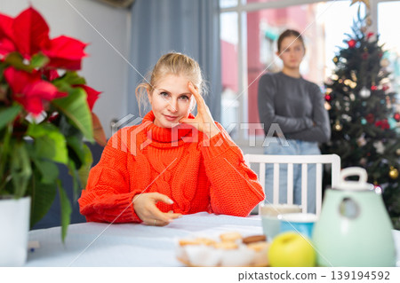 Mom sitting at table after quarreling with daughter during christmas time Mom sitting at table after quarreling with daughter during christmas time 139194592
