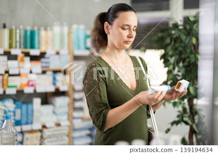 Middle-aged woman customer choosing ointment in box in drugstore Middle-aged woman customer choosing ointment in box in drugstore 139194634