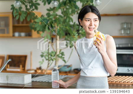 穿著運動服的亞洲年輕女子在廚房吃香蕉(訓練、補充能量、吃點心) 穿著運動服的亞洲年輕女子在廚房吃香蕉(訓練、補充能量、吃點心) 139194643