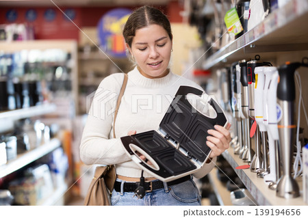 Young woman chooses electric waffle iron at supermarket 139194656