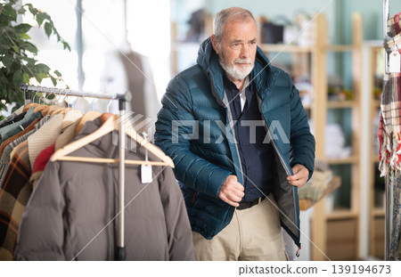 Elderly man trying on a down jacket Elderly man trying on a down jacket 139194673