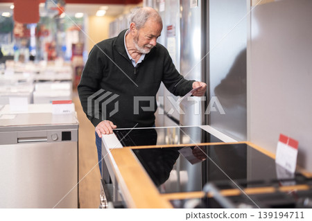 Elderly man chooses stove in appliance store Elderly man chooses stove in appliance store 139194711