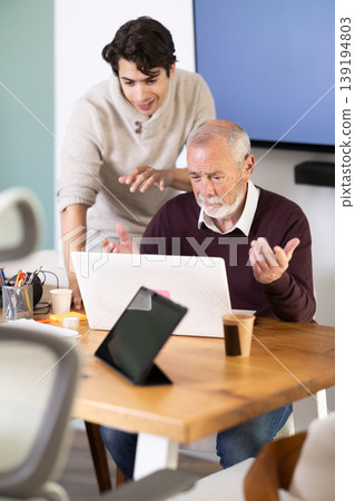 Guy helps elderly man complete task on laptop Guy helps elderly man complete task on laptop 139194803
