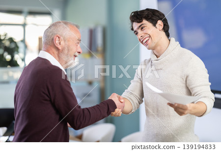 Smiling senior man makes deal, shaking hands with guy Smiling senior man makes deal, shaking hands with guy 139194833