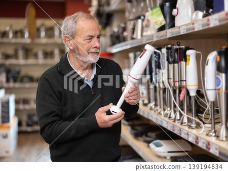 Elderly man chooses electric blender at supermarket Elderly man chooses electric blender at supermarket 139194834