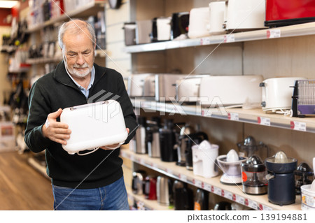 Elderly man choosing a toaster in a store Elderly man choosing a toaster in a store 139194881