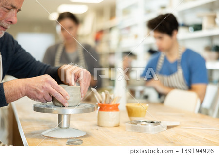 Close-up of elderly man's hands sculpting ceramic piece 139194926