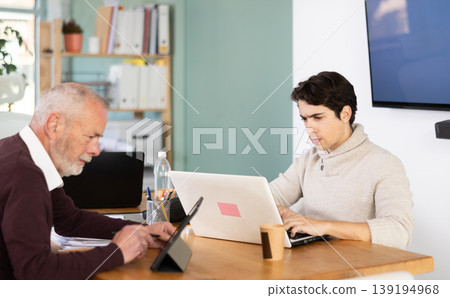 Two male manager work on laptops in modern company office Two male manager work on laptops in modern company office 139194968