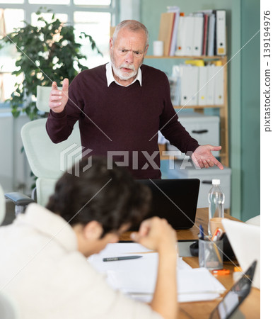 Mature male manager is dissatisfied with the work of an employee - yells and reproaches her Mature male manager is dissatisfied with the work of an employee - yells and reproaches her 139194976