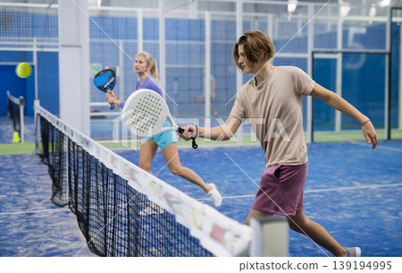 Guy playing paddle tennis on padel court indoors 139194995