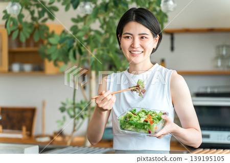 一位身穿運動服的年輕女子正在吃減肥餐 一位身穿運動服的年輕女子正在吃減肥餐 139195105