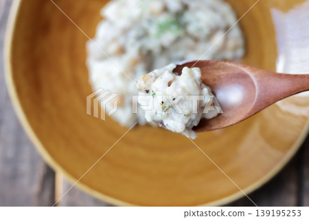 Picking up chicken and chickpea cream risotto with chopsticks 139195253