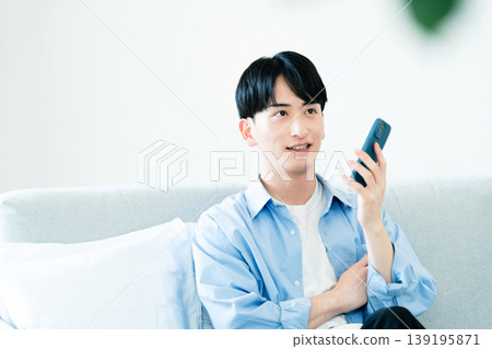 A man who uses a smartphone in the living room A man who uses a smartphone in the living room 139195871