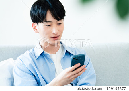 一個在客廳裡使用智能手機的人 139195877