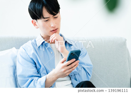 一個在客廳裡使用智能手機的人 139196111