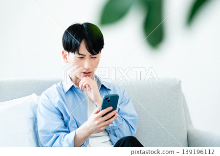 一個在客廳裡使用智能手機的人 139196112