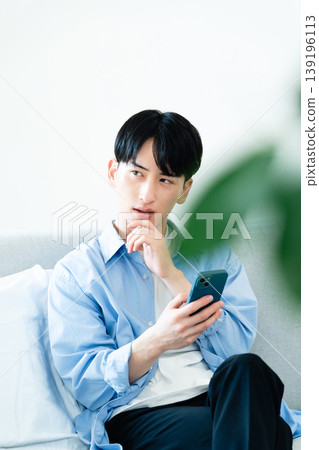 一個在客廳裡使用智能手機的人 139196113
