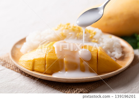 Pouring coconut milk sauce on Mango sticky rice (Khao Niew Mamuang),Thai dessert in summer season Pouring coconut milk sauce on Mango sticky rice (Khao Niew Mamuang),Thai dessert in summer season 139196201