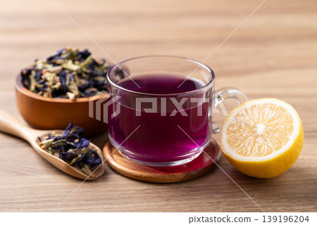 Hot butterfly pea tea in glass cup with lemon and dried flowers on wooden background Hot butterfly pea tea in glass cup with lemon and dried flowers on wooden background 139196204