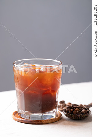 Iced americano coffee in a glass with roasted coffee beans. Popular refreshing summer drink Iced americano coffee in a glass with roasted coffee beans. Popular refreshing summer drink 139196208