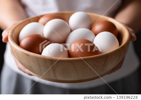 Organic white and brown eggs from free range farm in a wooden bowl holding by woman hand 139196228