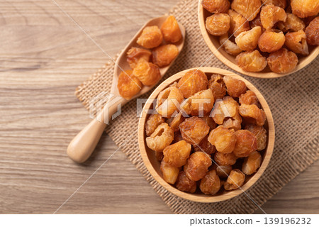 Dried longan in a wooden bowl with scoop on a wooden background, Table top view 139196232
