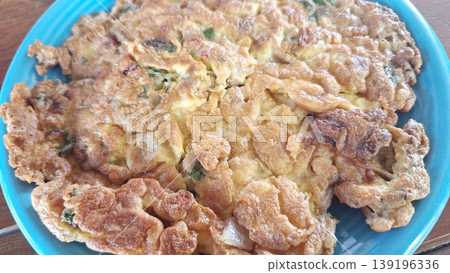 Golden brown and crispy Thai omelet seasoned with green onions, served as a traditional side dish in Thailand. 139196336