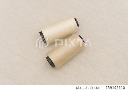 Two Beige Thread Spools on a Textured Surface Two Beige Thread Spools on a Textured Surface 139196610