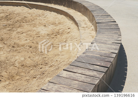 A sand pit with a curved wooden border in a sunny park	 139196616