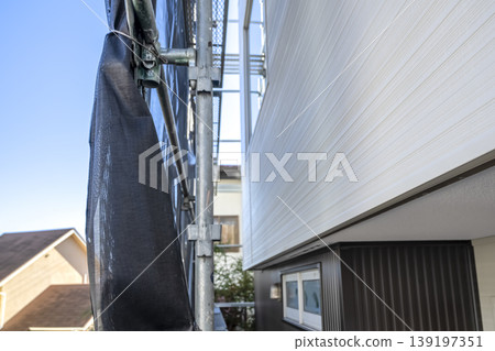 New exterior walls and scaffolding for a detached house: Close-up view of exterior construction work. 139197351