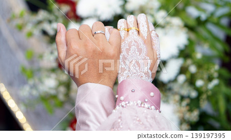 The bride and groom interlock their little fingers. The bride and groom interlock their little fingers. 139197395