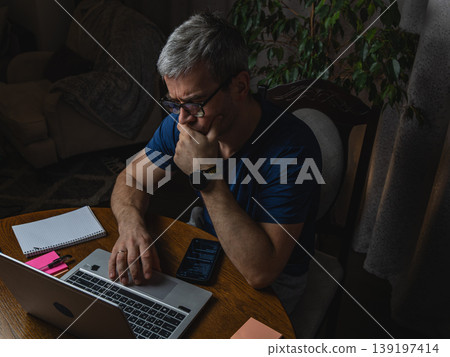 Thoughtful freelancer working on laptop at desk top view 139197414