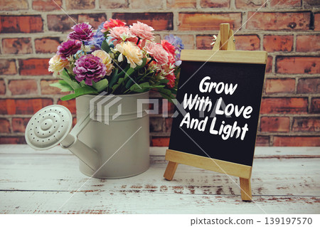 Grow With Love And Light text on black wooden easel and vase with flowers bouquet on brick wall background Grow With Love And Light text on black wooden easel and vase with flowers bouquet on brick wall background 139197570